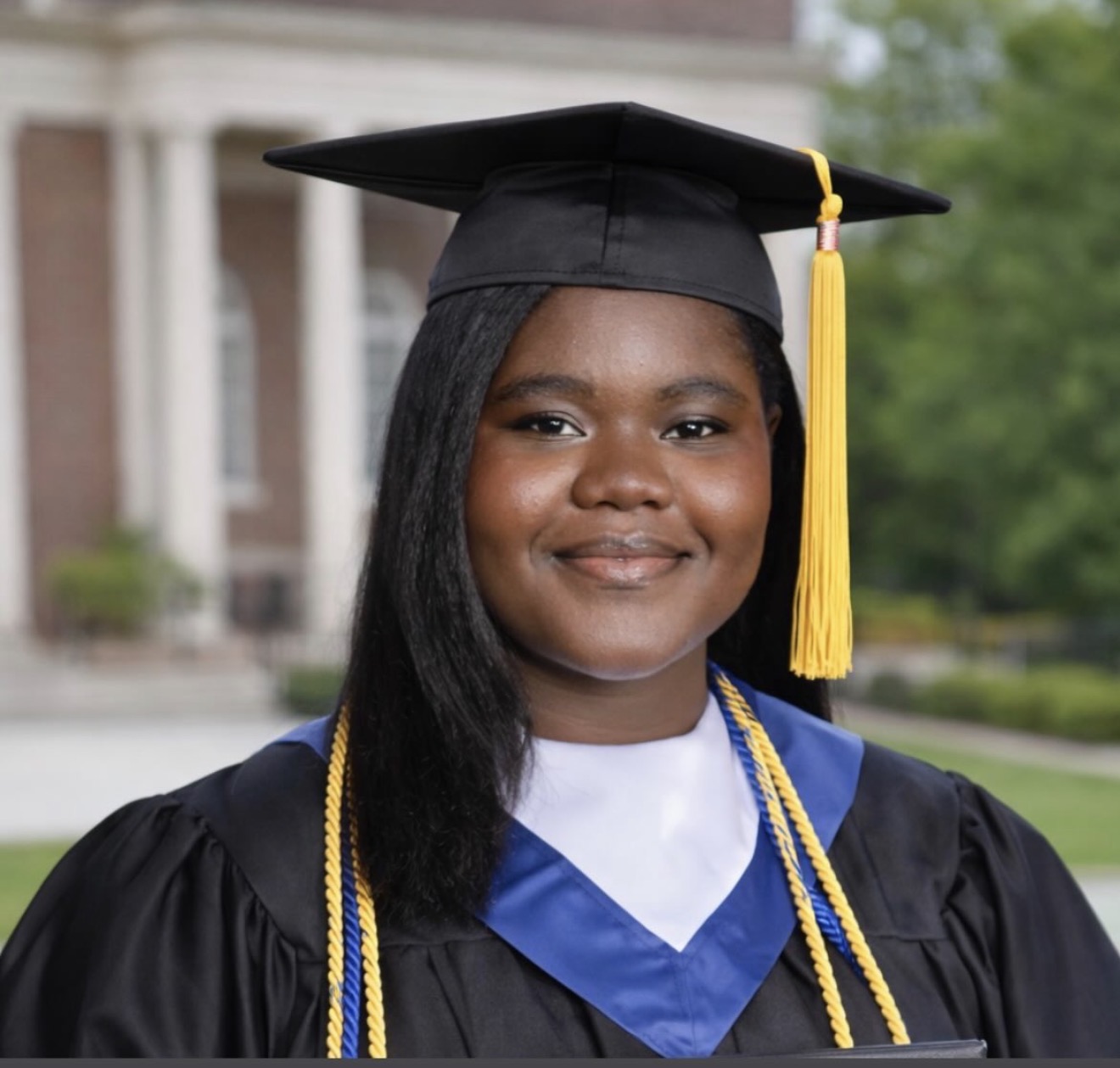 Mmeri scholar in cap, gown, and honor cords on graduation day