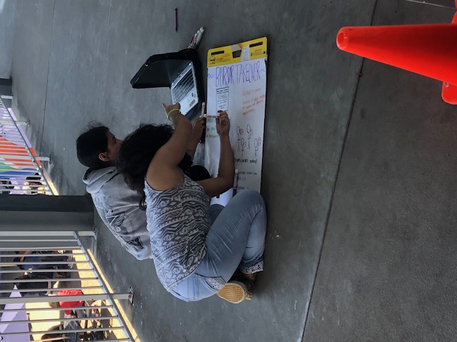 Students working together on a presentation poster at a community event