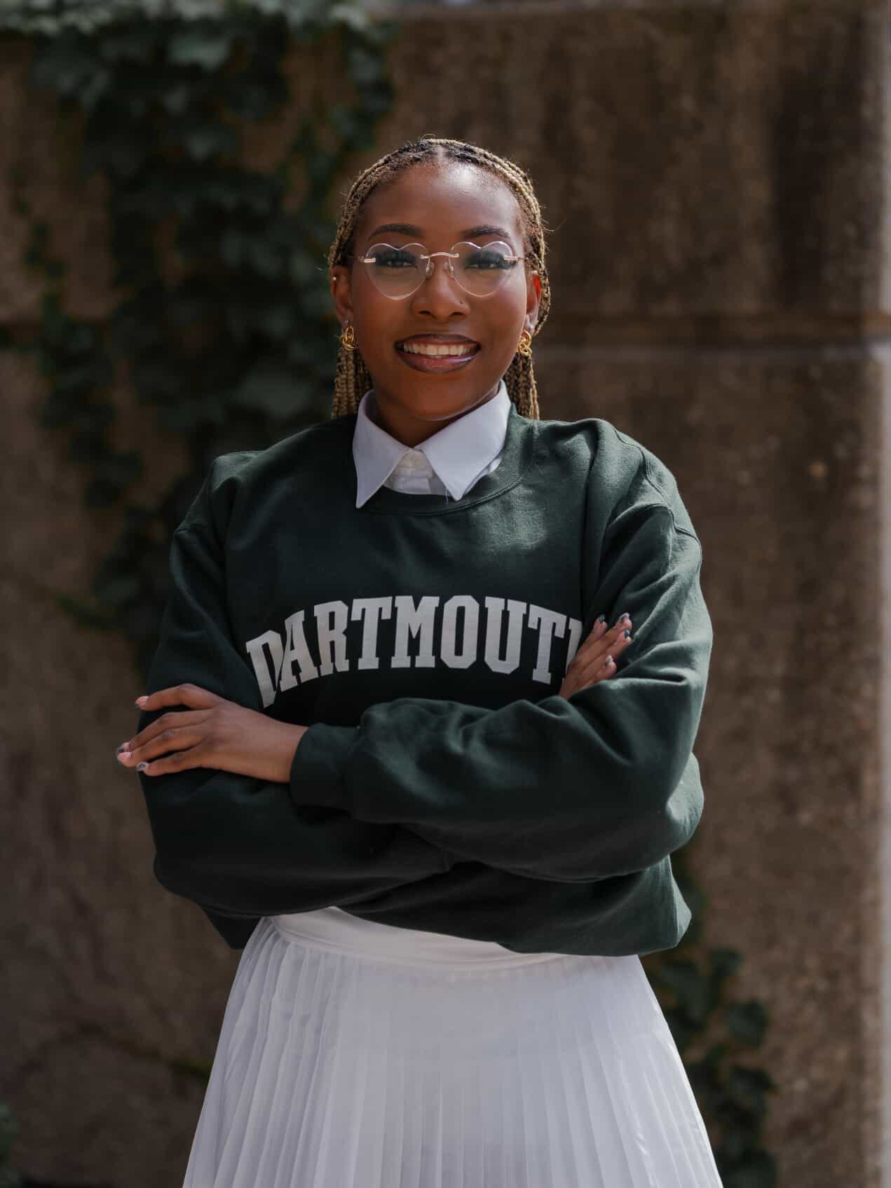 Young woman wearing a Dartmouth College sweatshirt smiling confidently with arms crossed