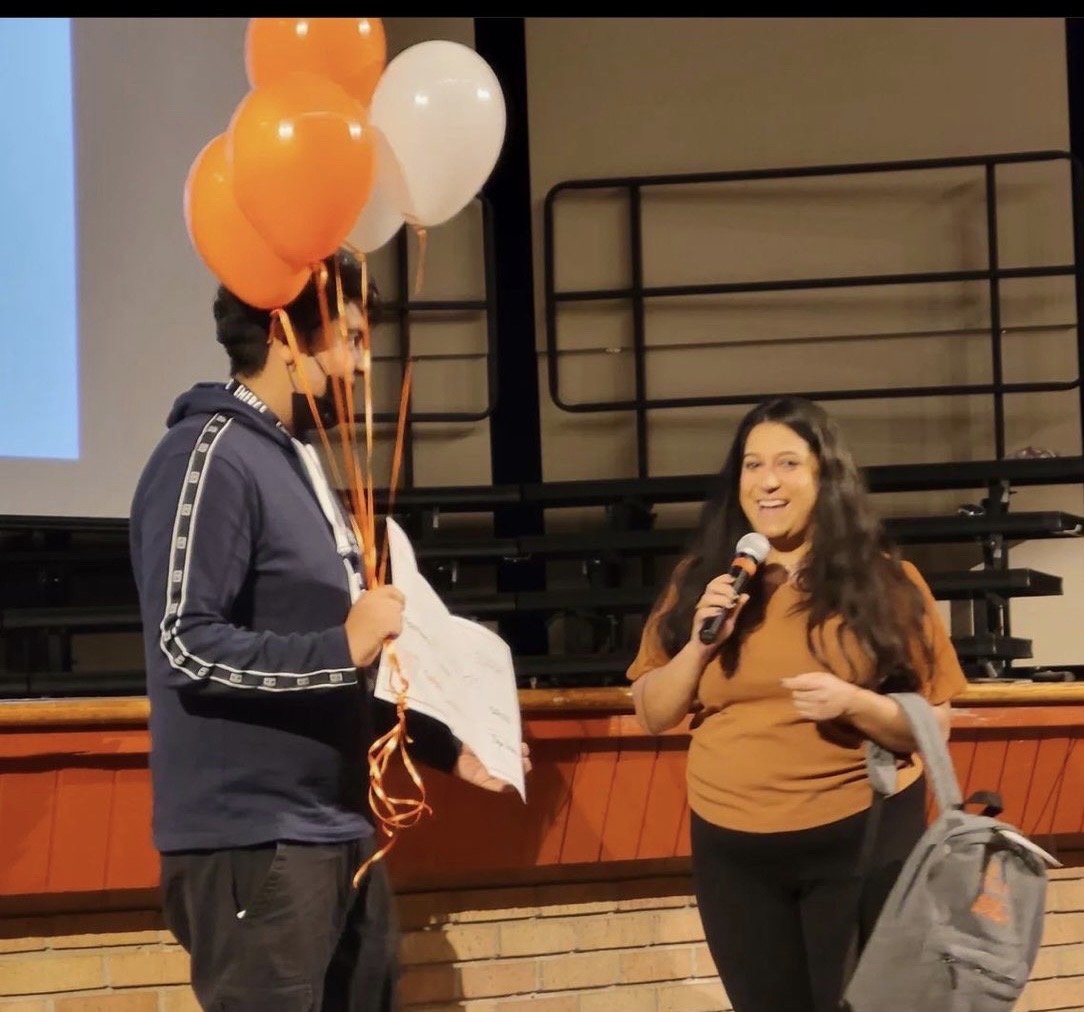Student receiving recognition with balloons at a school auditorium celebration
